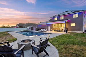 View of pool with an outdoor fire pit, a storage shed, a patio area, a fenced backyard, and a diving board