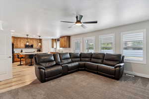 Living area with a textured ceiling, ceiling fan, light carpet, and recessed lighting