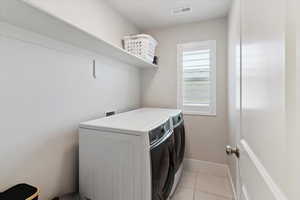 Laundry area with washing machine and clothes dryer and light tile patterned floors