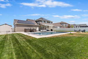 Rear view of property featuring a hot tub, roof mounted solar panels, a patio, and a fenced backyard