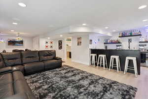 Living area featuring bar with sink, light wood finished floors, and recessed lighting