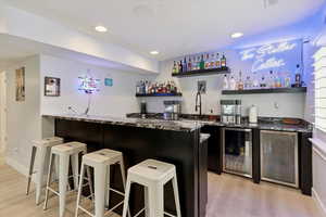 Indoor wet bar with wine cooler, light wood finished floors, and recessed lighting