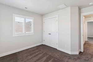 Unfurnished bedroom featuring dark carpet and a closet