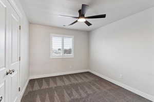 Unfurnished bedroom featuring dark carpet, a textured ceiling, and ceiling fan