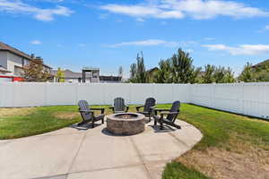 Fenced backyard featuring a fire pit and a patio
