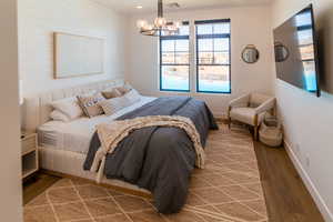 Bedroom featuring wood finished floors, a chandelier, and wooden walls