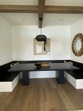 Unfurnished dining area with breakfast area, wood finished floors, beam ceiling, and wooden walls