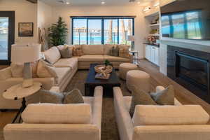 Living room with wood finished floors, a glass covered fireplace, and recessed lighting