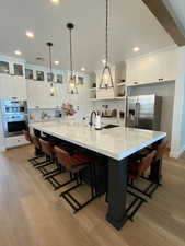 Kitchen with open shelves, appliances with stainless steel finishes, white cabinets, light wood-style floors, and recessed lighting
