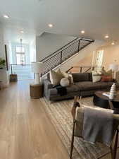 Living room featuring wood finished floors, recessed lighting, and stairs