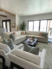 Living room featuring plenty of natural light, a textured ceiling, carpet floors, and beamed ceiling
