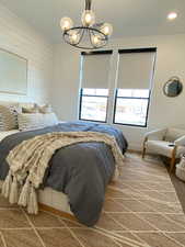 Bedroom featuring multiple windows, a chandelier, and wooden walls