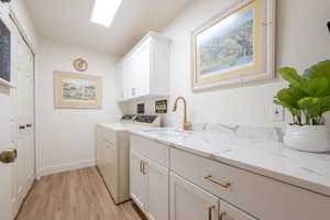 Washroom with cabinet space, washing machine and dryer, and light wood-style floors