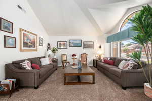 Carpeted living area with high vaulted ceiling