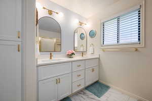 Bathroom with marble finish flooring, double vanity, a shower with shower door, and a textured ceiling