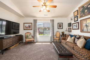 Living room featuring lofted ceiling, carpet flooring, and a ceiling fan