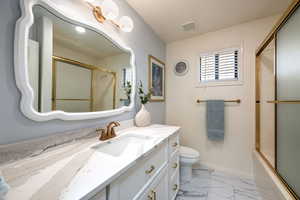 Bathroom with marble finish floors, vanity, and enclosed tub / shower combo