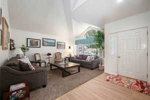 Living area with light wood-style flooring and vaulted ceiling