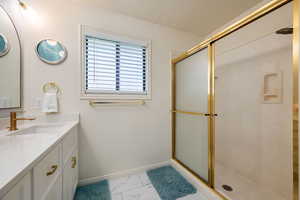 Full bathroom featuring vanity, a shower with shower door, marble look tiles, and a textured ceiling