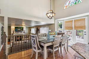 Dining space featuring wood finished floors, healthy amount of natural light, a fireplace, and a towering ceiling
