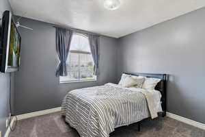 Carpeted bedroom featuring baseboards and a textured ceiling