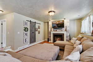 Living area featuring a textured ceiling, wood finished floors, a barn door, and a fireplace