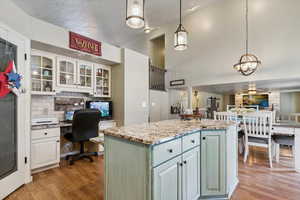 Kitchen with light wood-style flooring, white cabinetry, built in study area, open floor plan, and a high ceiling