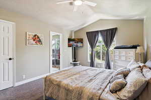 Carpeted bedroom featuring multiple windows, lofted ceiling, a ceiling fan, and a textured ceiling