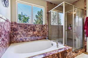 Bathroom featuring healthy amount of natural light, a bath, and a stall shower