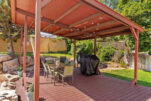Wooden terrace with a fenced backyard, outdoor dining area, and grilling area