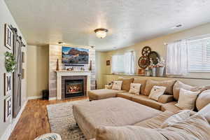 Living room featuring light wood finished floors, a textured ceiling, and a tile fireplace