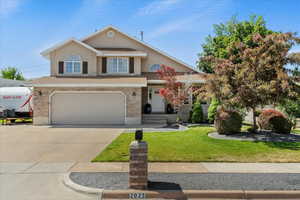 Traditional home featuring driveway, a garage, a front yard, stucco siding, and brick siding