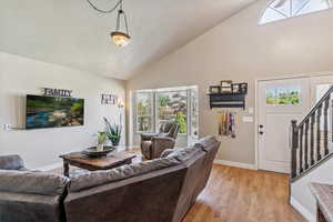 Living area with light wood finished floors, stairway, and high vaulted ceiling