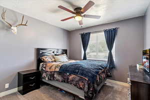 Carpeted bedroom featuring a textured ceiling and ceiling fan