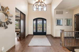 Entrance foyer with wood-type flooring, arched walkways, a chandelier, and a high ceiling