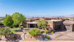 View of front of home with driveway, a garage, a mountain view, stucco siding, and stone siding