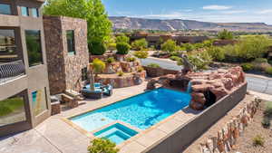 View of pool with a mountain view, a pool with connected hot tub, and a patio
