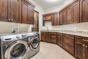 Laundry room with cabinet space, washer and clothes dryer, and light tile patterned floors