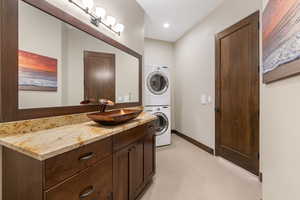 Bathroom with stacked washer / drying machine, vanity, and recessed lighting