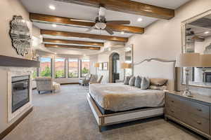 Bedroom with beam ceiling, a tile fireplace, recessed lighting, carpet floors, and arched walkways