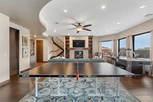 Recreation room with a ceiling fan, recessed lighting, a glass covered fireplace, and hardwood / wood-style flooring