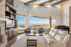 Living area featuring dark wood-style floors, beamed ceiling, and a towering ceiling