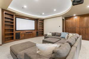 Home theater with light carpet, recessed lighting, and a raised ceiling