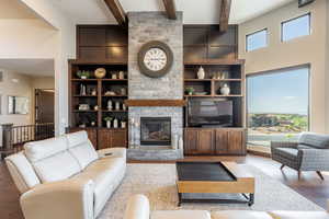 Living area featuring wood finished floors, beamed ceiling, a large fireplace, and a towering ceiling