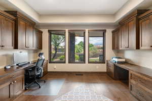 Office with built in study area and dark wood-style flooring