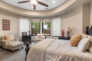Carpeted bedroom featuring a tray ceiling, ceiling fan, and recessed lighting