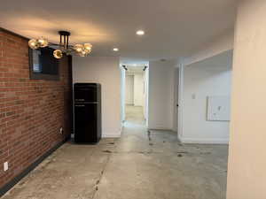 Unfurnished dining area featuring brick wall, recessed lighting, concrete floors, and a chandelier