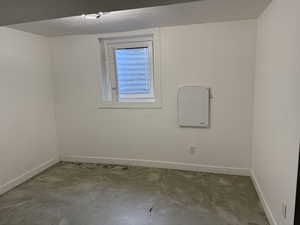Empty room with a textured ceiling and unfinished concrete flooring