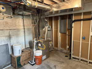 Utility room with electric panel, water heater, and heating unit