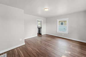 Spare room featuring healthy amount of natural light and dark wood-style flooring